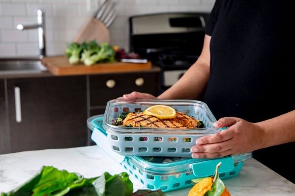 Woman meal prepping food into multiple reusable containers